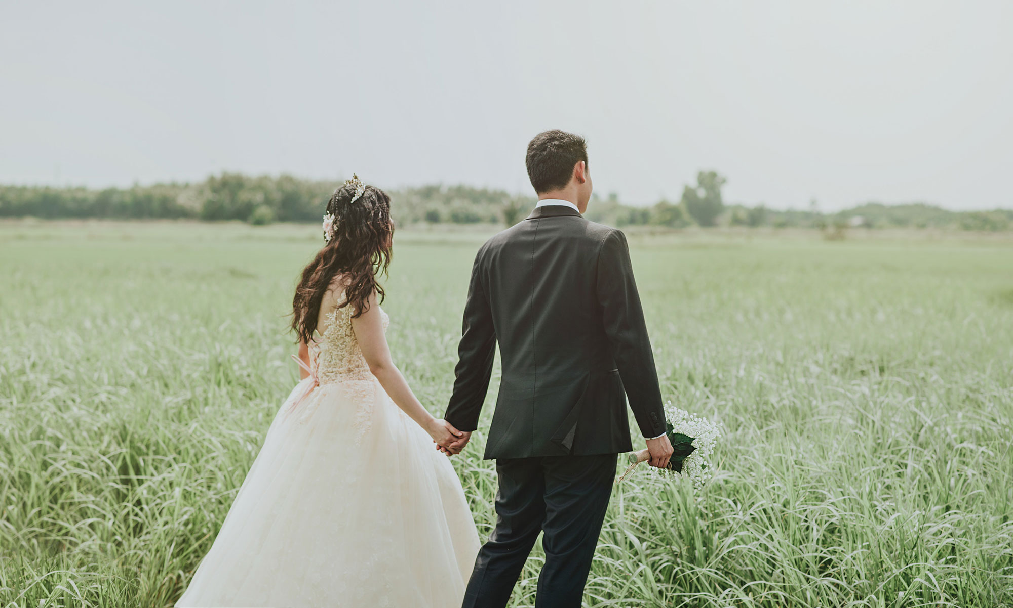Bride and groom walking in a field